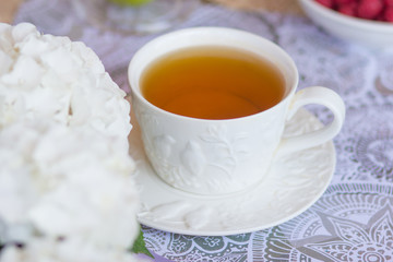 A festive morning breakfast, tea with croissants, muffins and raspberries on a background of white flowers