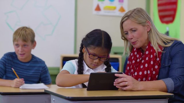 Teacher and student using digital tablet in school classroom