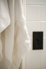 Weisses Handtuch vor weiss gekachelter Wand mit Lichtschalter