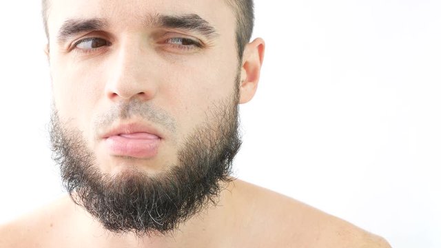 Close-up of naked bearded sly prankster making funny faces, studio isolated on white background.