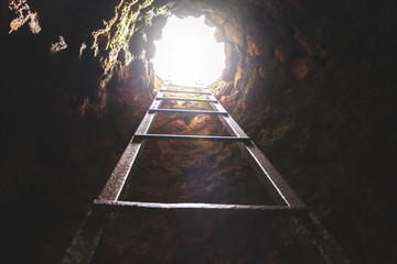 cave hole with rustic ladder on wood and the light in out hole - obrazy, fototapety, plakaty