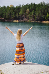 Woman traveling near lake, feeling freedom with hands up