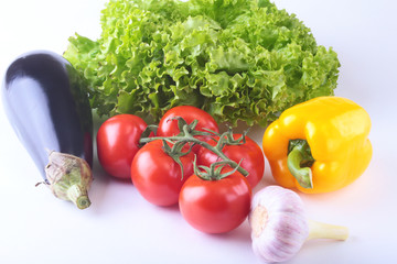 Fresh assorted vegetables, eggplant, bell pepper, tomato, garlic with leaf lettuce. Isolated on white background. Selective focus.