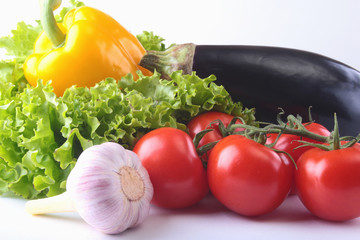 Fresh assorted vegetables, eggplant, bell pepper, tomato, garlic with leaf lettuce. Isolated on white background. Selective focus.