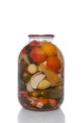 Canned tomatoes and cucumbers in a glass jar on a white background.
