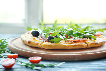 Tasty pizza cherry tomatoes, olives and arugula on blue wooden table