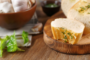 Slice of tasty bread with garlic and herbs on wooden table, close up