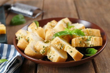 Plate with slices of tasty garlic bread on wooden table
