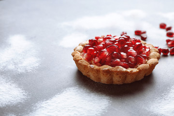 Tasty tart with fresh seeds of pomegranates on table