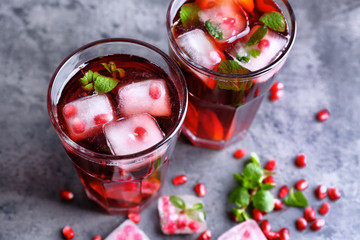 Two glasses of cold fruit cocktail on gray background