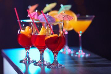 Glasses with tasty cocktails on bar counter against blurred background