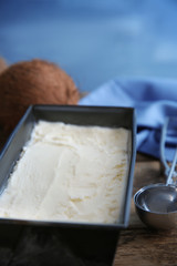 Black container with fresh coconut ice cream on wooden table