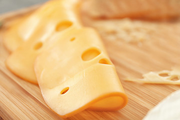 Sliced cheese on wooden board, closeup