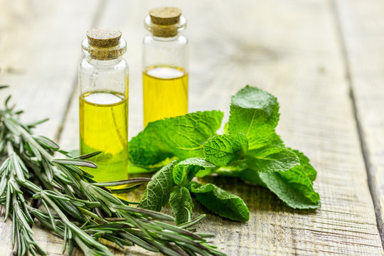 natural cosmetic oil with fresh rosemary and mint on light wooden table background