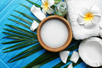 Spa composition with coconut milk and palm leaf on wooden background