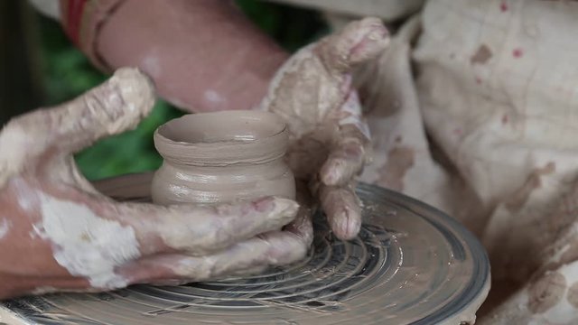 Hands of a potter and his apprentice. Man and woman makes a pot on pottery wheel. Woman is the pupil of a potter. Man and woman hands