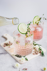making cocktails in glasses with lime and herbs on stone kitchen desk background