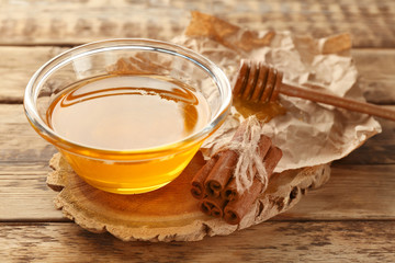 Cinnamon and honey in bowl on wooden background