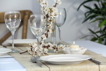 Beautiful festive table setting and branch of flowers in light room