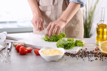 Woman cutting lettuce on kitchen table