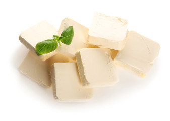 Delicious butter pieces with basil leaves on white background, closeup