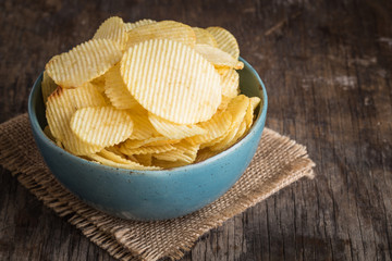 Potato chips in a blue bowl on an old wood table.