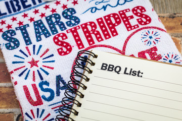 BBQ list concept on notebook and wooden board and Stars and Stripes banner for patriotic themed event