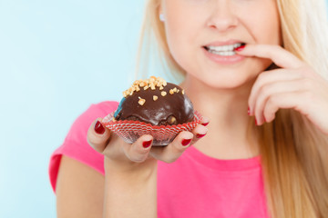 Woman holding chocolate cupcake about to bite