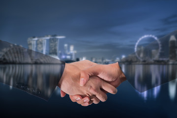 Double Exposure of a businessman handshake on blue tone Singapore city blurred background.