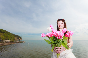 Woman holding bouquet of flowers on seaside