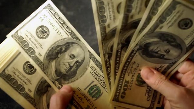 Female hands count a pack of 100 dollar bills. Zoom of the image in motion.