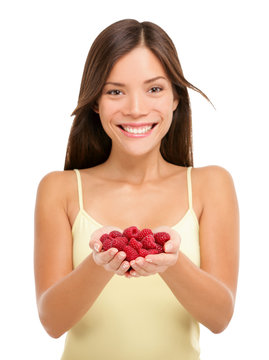 Woman holding fresh raspberries in hands closeup isolated on white background. Portrait of Asian woman showing handful of red raspberries in woman hands. Raspberry fruit berry concept.