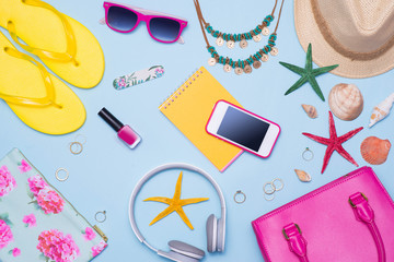 Summer concept. Pink handbag with accessories on light blue background