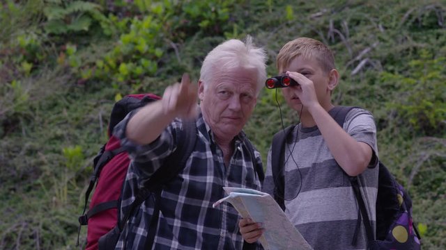Senior man looking through binoculars with grandson