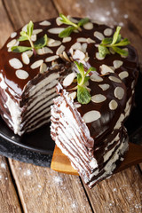 piece of chocolate crepe cake with whipped cream and almonds close-up vertical