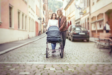 Fototapeta na wymiar Young Parents With Baby Stroller In The City