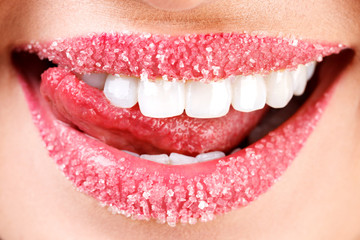 Closeup of woman's lips covered with sugar. Toothy smile