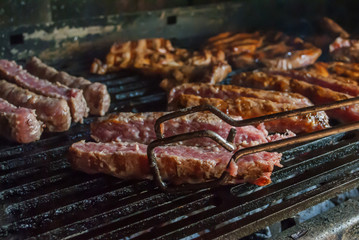 Turning minced meat "cevapcici" with grill tongs