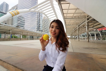 Portrait of attractive Asian business woman with yellow ball in the city background.