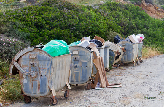 Four overloaded wheeled trashbins
