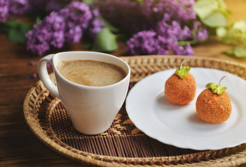 A lilac, a cake and a cappuccino are on the table.