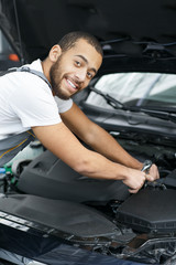 Naklejka na ściany i meble Professional car mechanic repairing a car