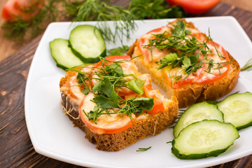 Бутерброды с помидором, сыром и зеленью на тарелке