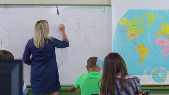 Teacher asks students math questions in school classroom
