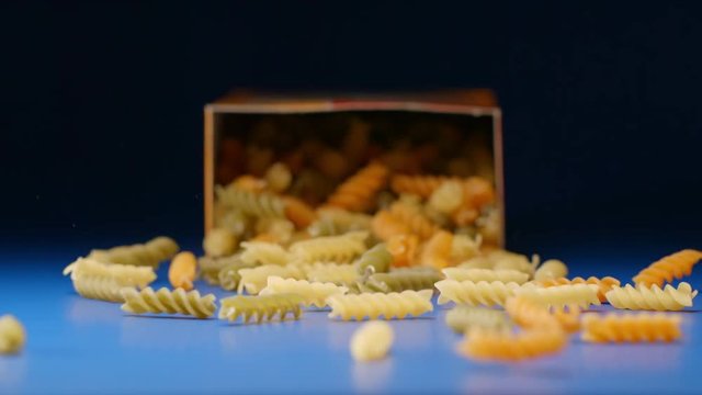 SLOW MOTION: Falling a box with a colour spiral pasta (fusilli)