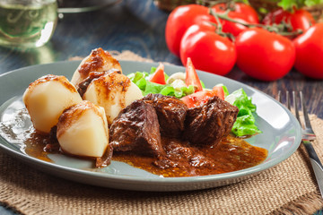 Pork meat stew served with potatoes and vegetable salad