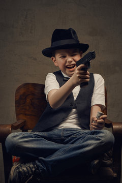 Little boy gangster in hat with weapon