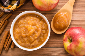 Яблочное пюре, яблоки и корица на деревянном столе. 