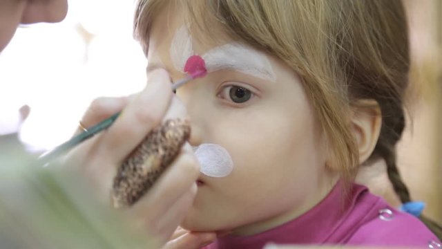 Child face painting like a cat
