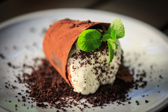 Chocolate dessert with mint and cream in the form of a fallen planter.